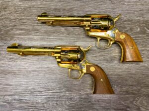 Pair of highly decorated, gold-finished Colt Single Action Army revolvers from the "America Remembers" series, with a custom double holster rig.