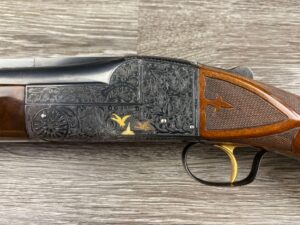 Rare Ithaca Single Shot Model 7E 12 gauge shotgun, a two-barrel set with gold inlays and intricate vine engraving, in a canvas hardcase.