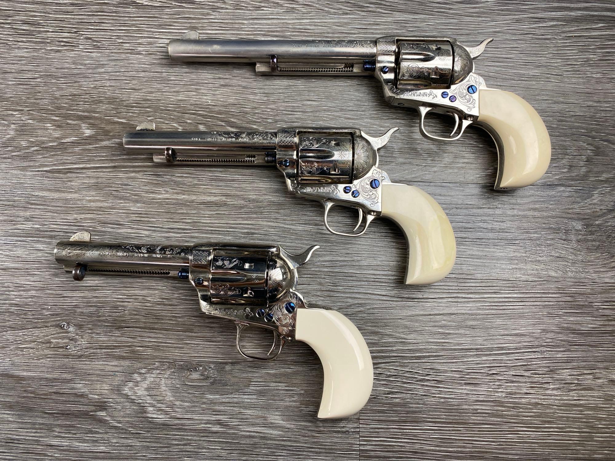 Set of three engraved Colt Custom Workshop 3rd Generation Single Action Army revolvers with nickel finish, white grips, and a factory presentation case.