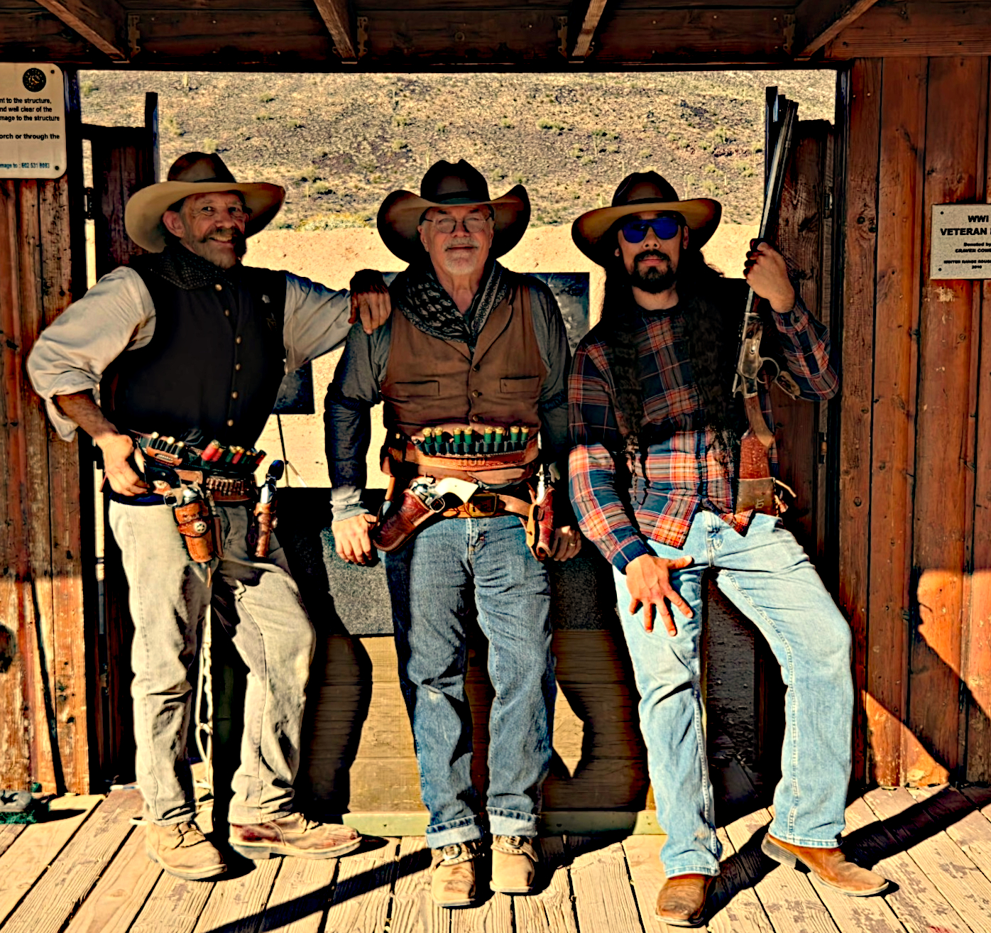Mark Romano, Jeff Taverner, and Jimi Murtagh at a cowboy action shooting range, dressed in period western attire and carrying period-appropriate firearms